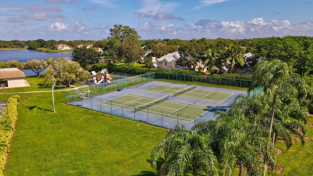 view of tennis court with a playground, a water view, and a yard