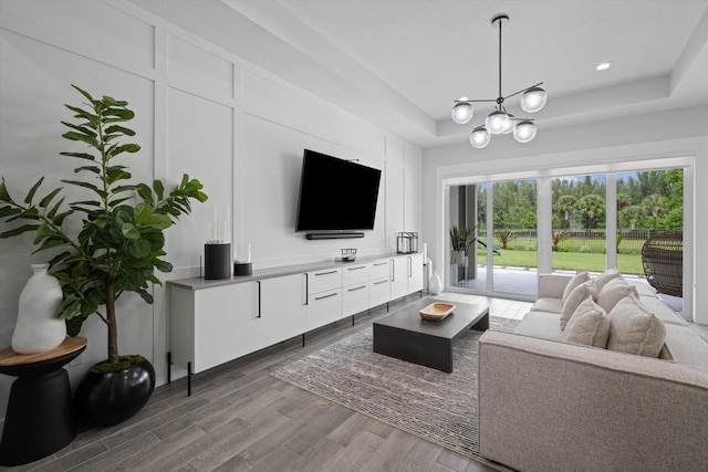 living room featuring a raised ceiling, hardwood / wood-style flooring, and an inviting chandelier