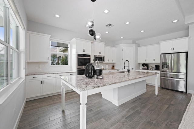 kitchen featuring decorative light fixtures, white cabinets, sink, and stainless steel appliances