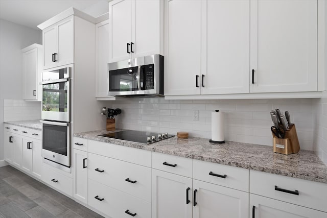 kitchen with backsplash, hardwood / wood-style floors, appliances with stainless steel finishes, white cabinets, and light stone counters