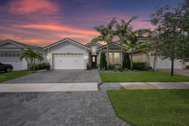 ranch-style house featuring a garage and a lawn