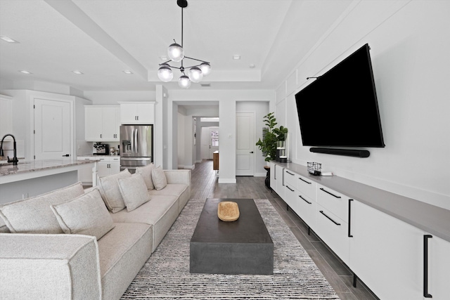 living room featuring a tray ceiling and sink