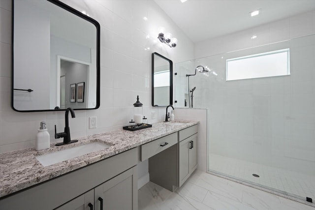 bathroom with vanity, decorative backsplash, tile walls, and tiled shower