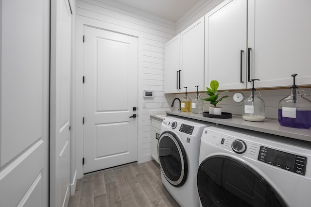 laundry area with light wood-type flooring, cabinets, washer and clothes dryer, and sink