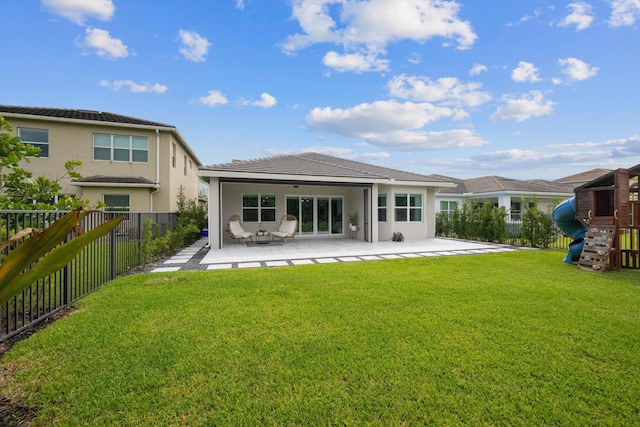 back of property with a playground, a lawn, and a patio