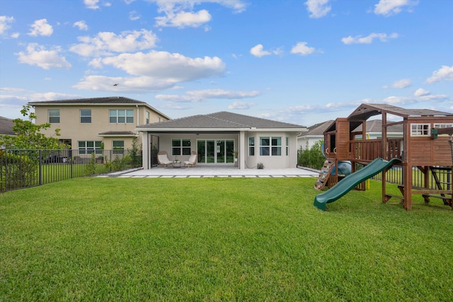 rear view of property with a playground, a yard, and a patio