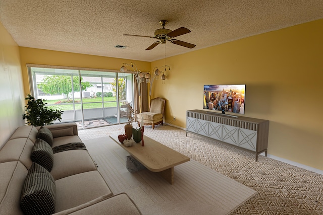 living room with ceiling fan, a textured ceiling, and carpet