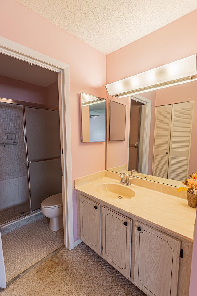 bathroom featuring vanity, an enclosed shower, a textured ceiling, and toilet