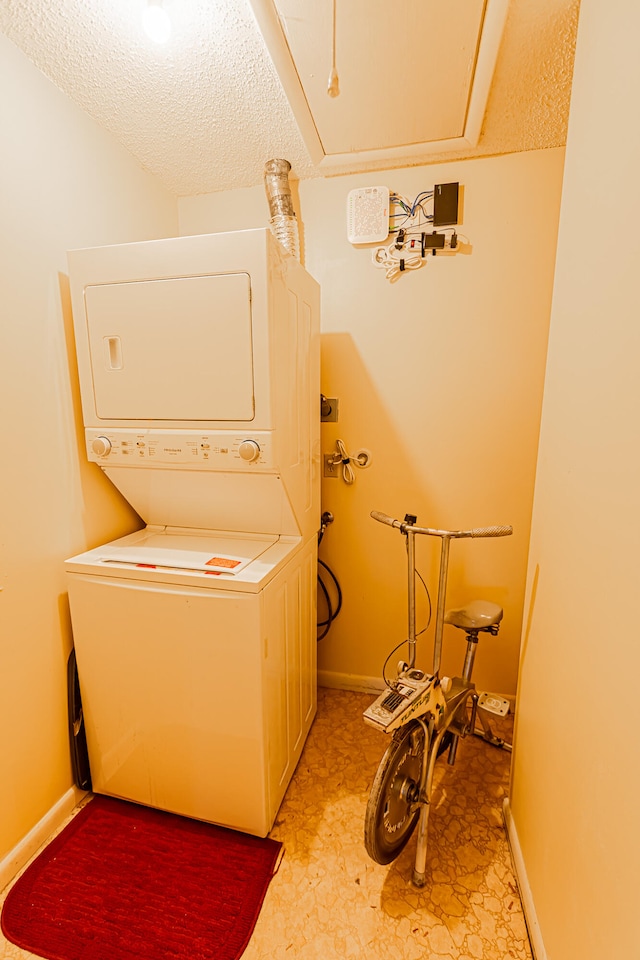 clothes washing area featuring a textured ceiling and stacked washer / dryer