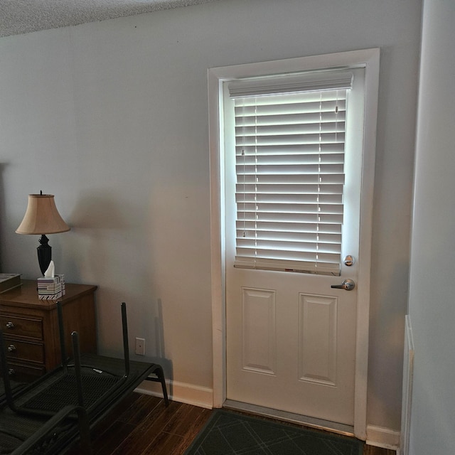 doorway to outside featuring a textured ceiling and dark wood-type flooring