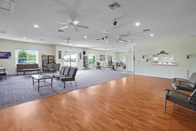 living room with ceiling fan, a textured ceiling, and hardwood / wood-style flooring