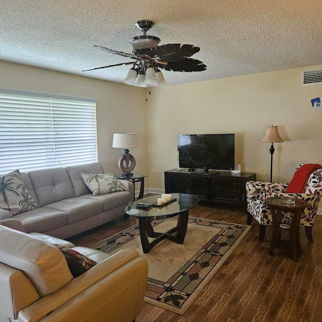 living room featuring ceiling fan, dark wood-type flooring, and a textured ceiling