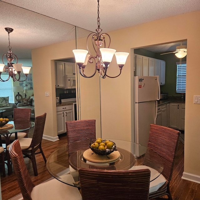 dining space with ceiling fan with notable chandelier, dark hardwood / wood-style floors, and a textured ceiling