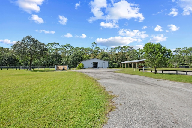 view of front of home featuring a front yard, an outdoor structure, and a rural view