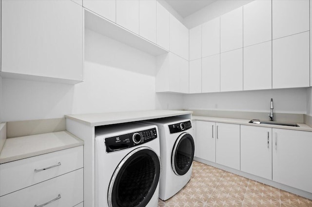 clothes washing area featuring washing machine and dryer, sink, and cabinets