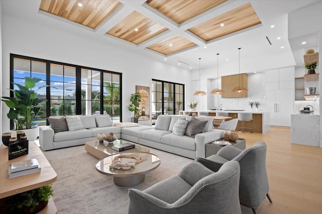 living room featuring wooden ceiling, light wood-type flooring, beamed ceiling, a towering ceiling, and coffered ceiling