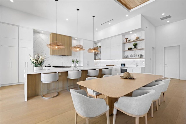 dining room with a towering ceiling, sink, and light wood-type flooring