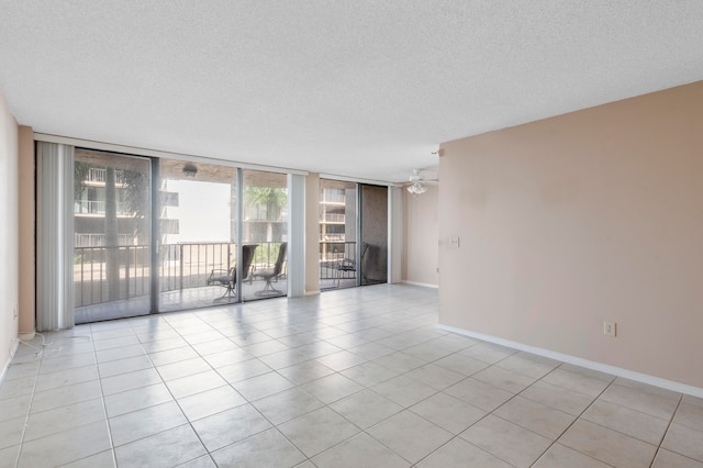 unfurnished room with expansive windows, a textured ceiling, light tile patterned floors, and ceiling fan