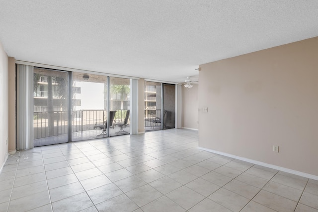 empty room featuring a textured ceiling, ceiling fan, baseboards, floor to ceiling windows, and light tile patterned floors