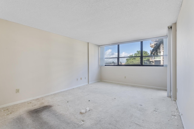 empty room featuring carpet floors, a textured ceiling, and baseboards