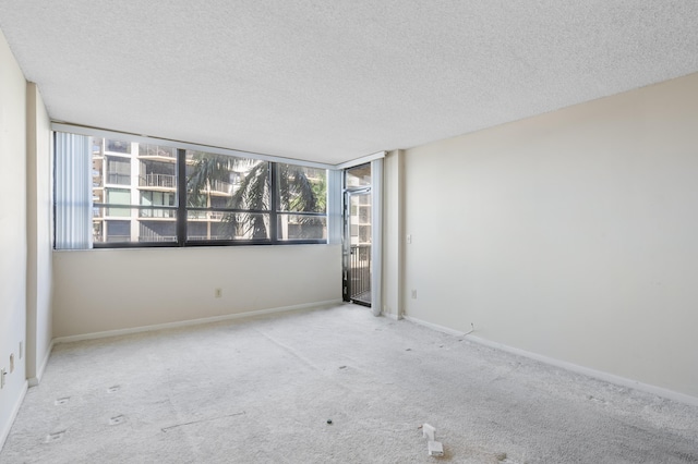 carpeted empty room with a textured ceiling and baseboards