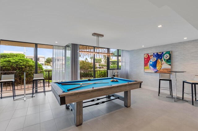 game room featuring a notable chandelier, billiards, light tile patterned flooring, and a wall of windows