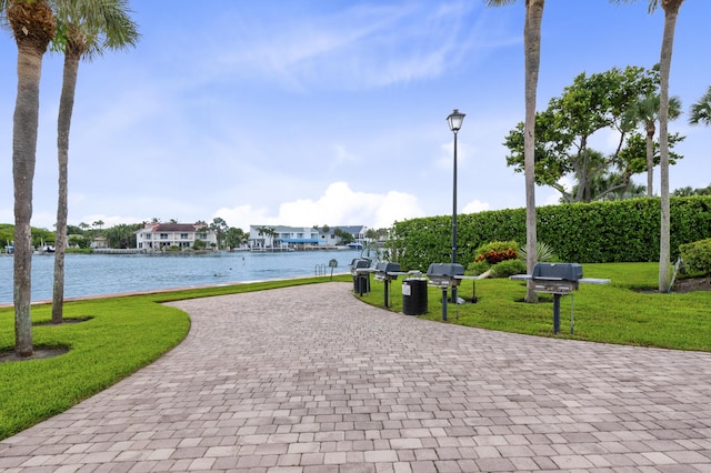 view of property's community with a yard, a water view, driveway, and a residential view