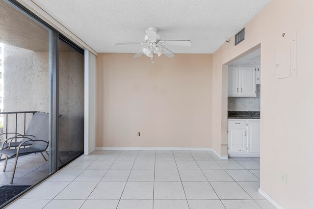 unfurnished dining area featuring ceiling fan, a textured ceiling, and light tile patterned floors