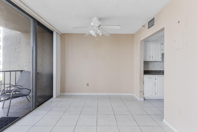 unfurnished room featuring ceiling fan, a textured ceiling, baseboards, and light tile patterned floors