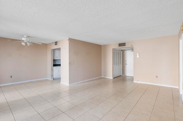 tiled empty room featuring ceiling fan and a textured ceiling