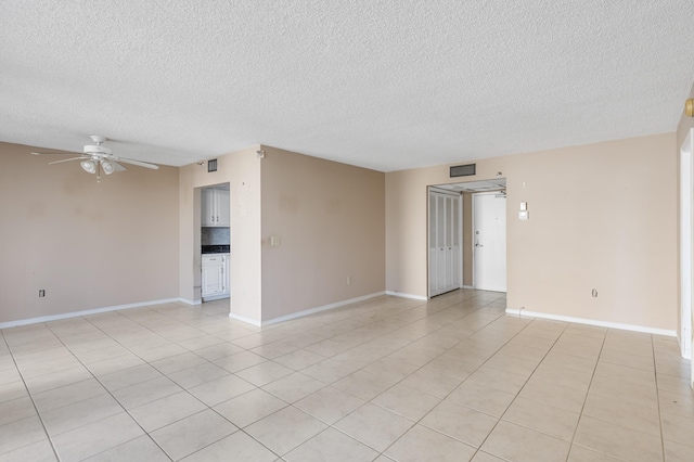 unfurnished room with a ceiling fan, a textured ceiling, light tile patterned flooring, and baseboards