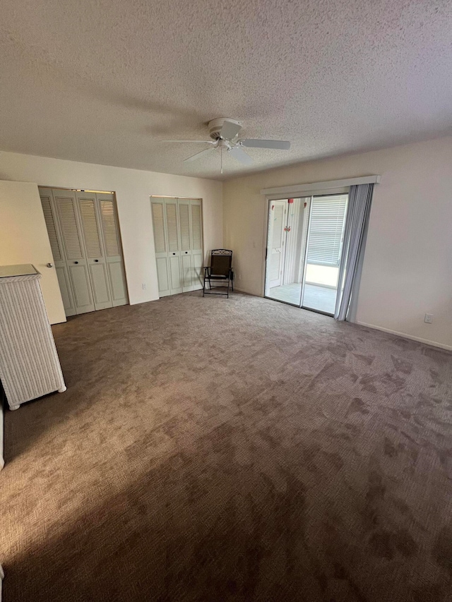 interior space featuring carpet, a textured ceiling, ceiling fan, and multiple closets