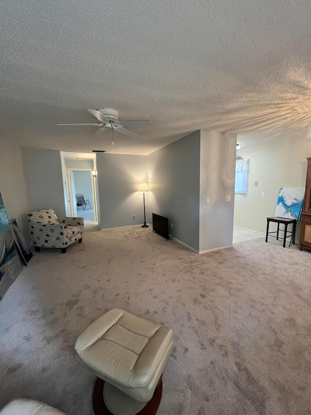 living room featuring carpet flooring, a textured ceiling, and ceiling fan