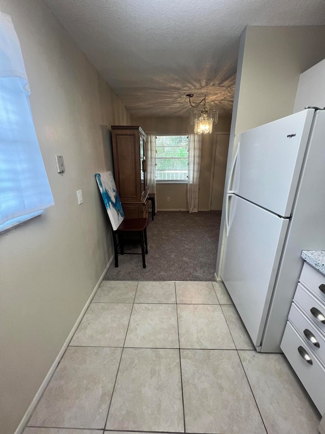 kitchen with light tile patterned floors, white fridge, decorative light fixtures, and an inviting chandelier