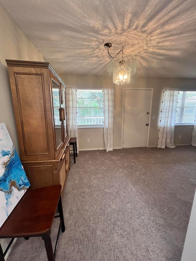 interior space featuring carpet, a healthy amount of sunlight, a textured ceiling, and a notable chandelier