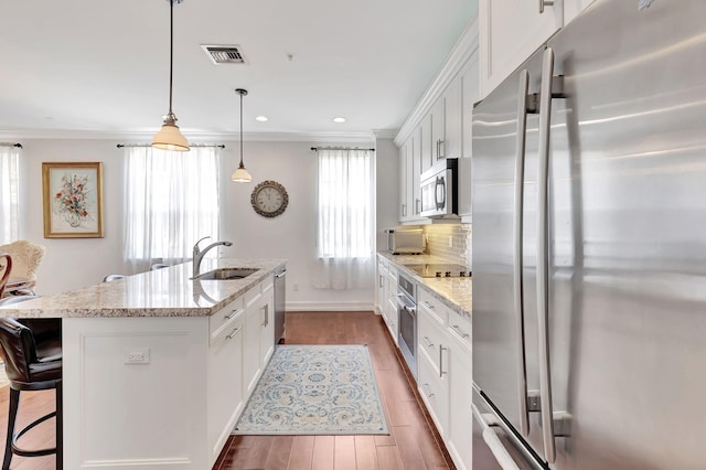 kitchen featuring white cabinets, hardwood / wood-style floors, stainless steel appliances, and a center island with sink