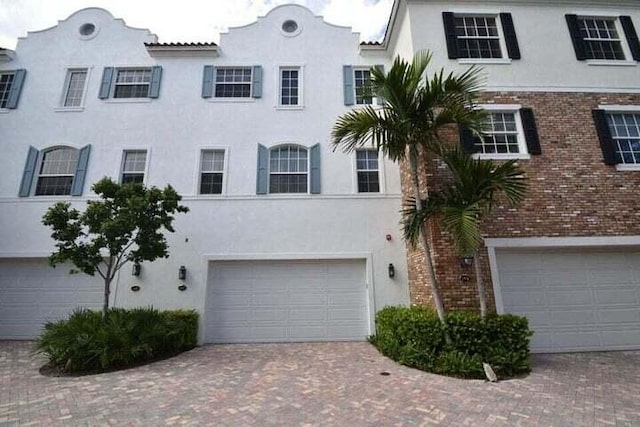 view of front of home with stucco siding, an attached garage, and decorative driveway