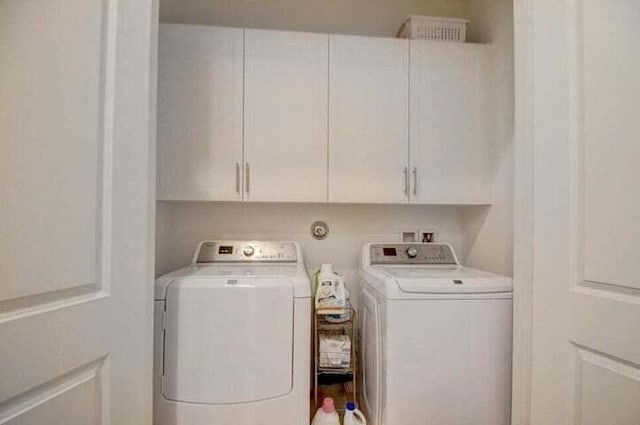 clothes washing area with cabinets and washing machine and dryer