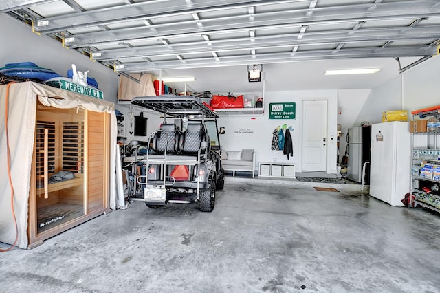 garage with stainless steel refrigerator, white fridge, and a garage door opener