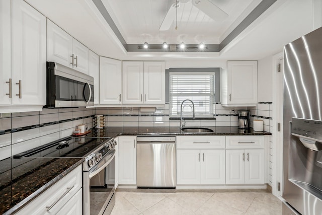 kitchen with sink, appliances with stainless steel finishes, white cabinets, and a raised ceiling