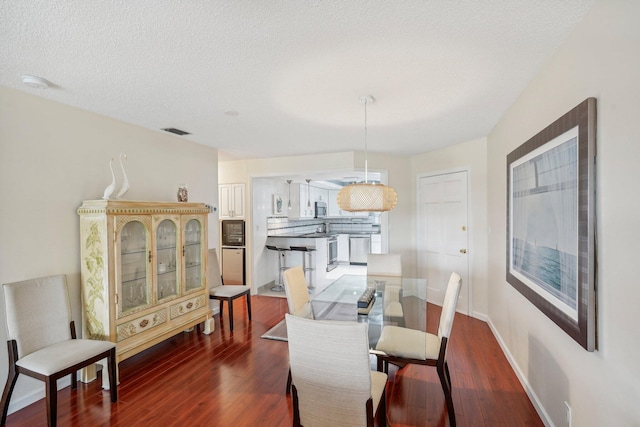 dining room with a textured ceiling and dark hardwood / wood-style flooring