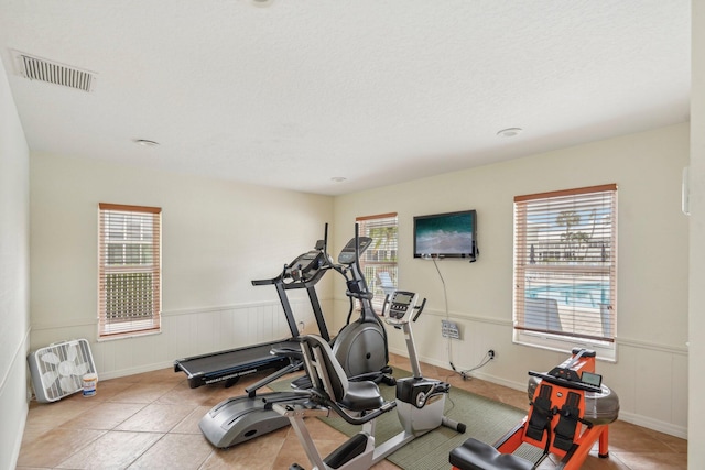 workout area featuring a textured ceiling and light tile patterned floors