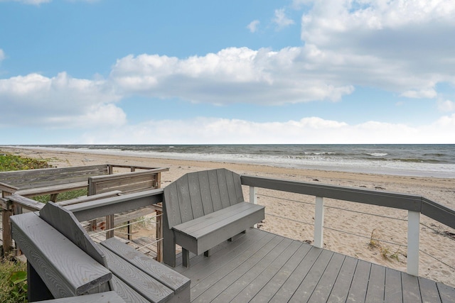 wooden deck featuring a water view and a beach view