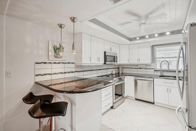 kitchen featuring appliances with stainless steel finishes, kitchen peninsula, pendant lighting, and white cabinetry