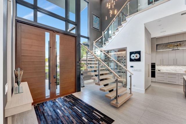 200 NE 6th St, Boca Raton, FL 33432 - entryway featuring light tile patterned floors, stairs, baseboards, and a towering ceiling