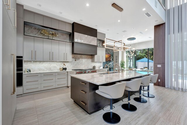 200 NE 6th St, Boca Raton, FL 33432 - kitchen featuring a kitchen breakfast bar, gray cabinets, modern cabinets, visible vents, and tasteful backsplash