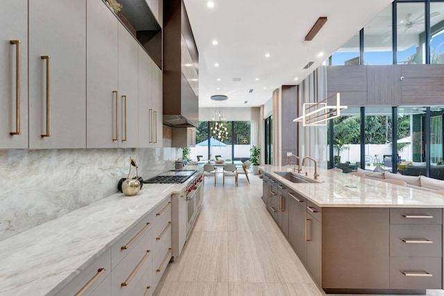 kitchen featuring a spacious island, hanging light fixtures, sink, light stone countertops, and a chandelier