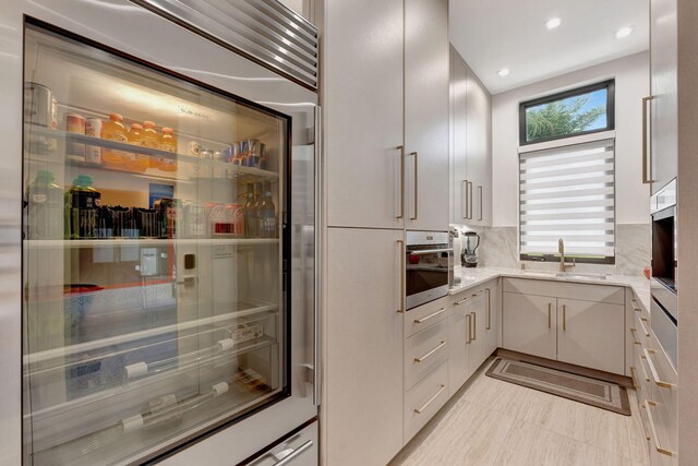 kitchen with light stone countertops, appliances with stainless steel finishes, sink, decorative backsplash, and light tile patterned floors