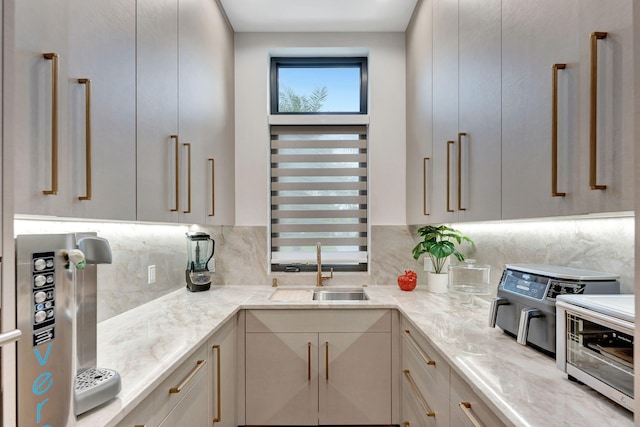 kitchen featuring decorative backsplash, light stone counters, and sink