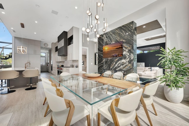 dining space with a towering ceiling, light hardwood / wood-style flooring, and sink